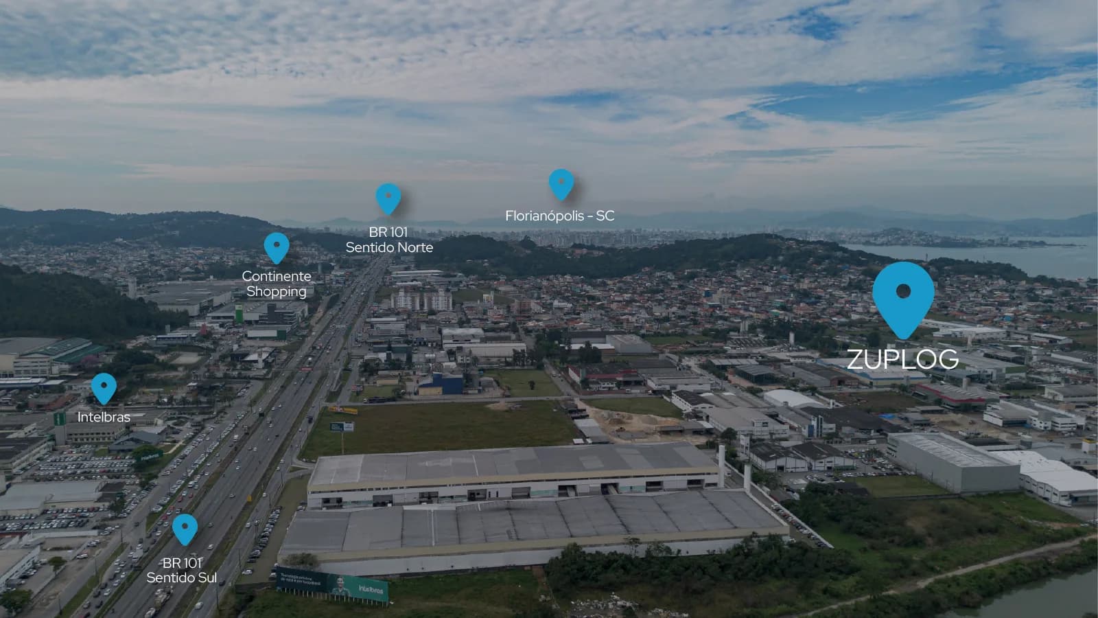 Vista aérea de São José (SC) com a localização da Zuplog, a BR-101 e Florianópolis ao fundo